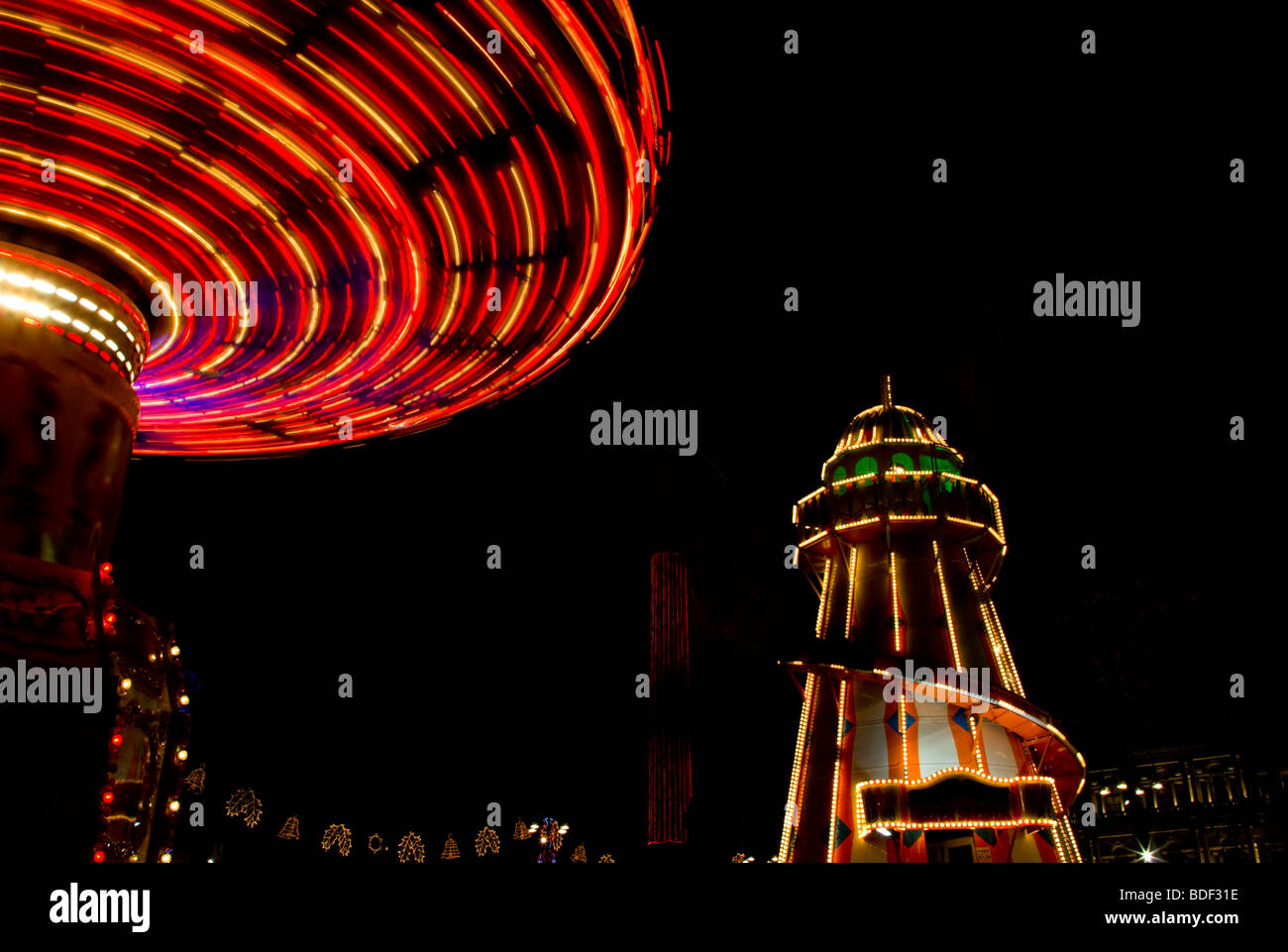 A spinning fairground carousel and helter skelter at night Stock Photo