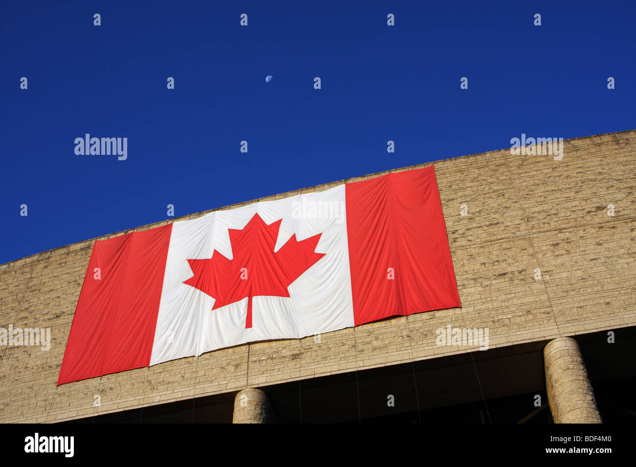 Moon in the blue sky above the Canadian flag. Stock Photo