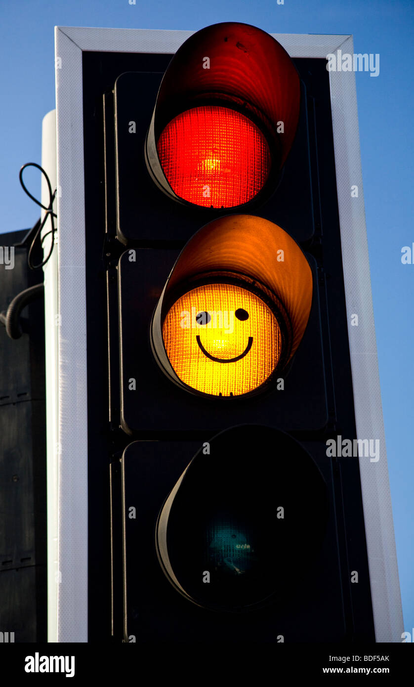 Traffic lights with a smiley face drawn on the amber light Stock Photo
