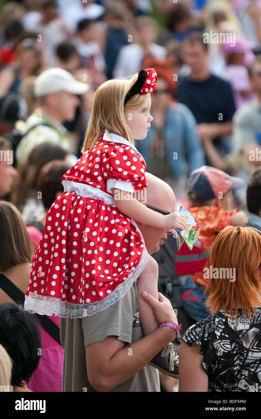 A young girl in Minnie Mouse costume sits on her fathers shoulders Stock Photo