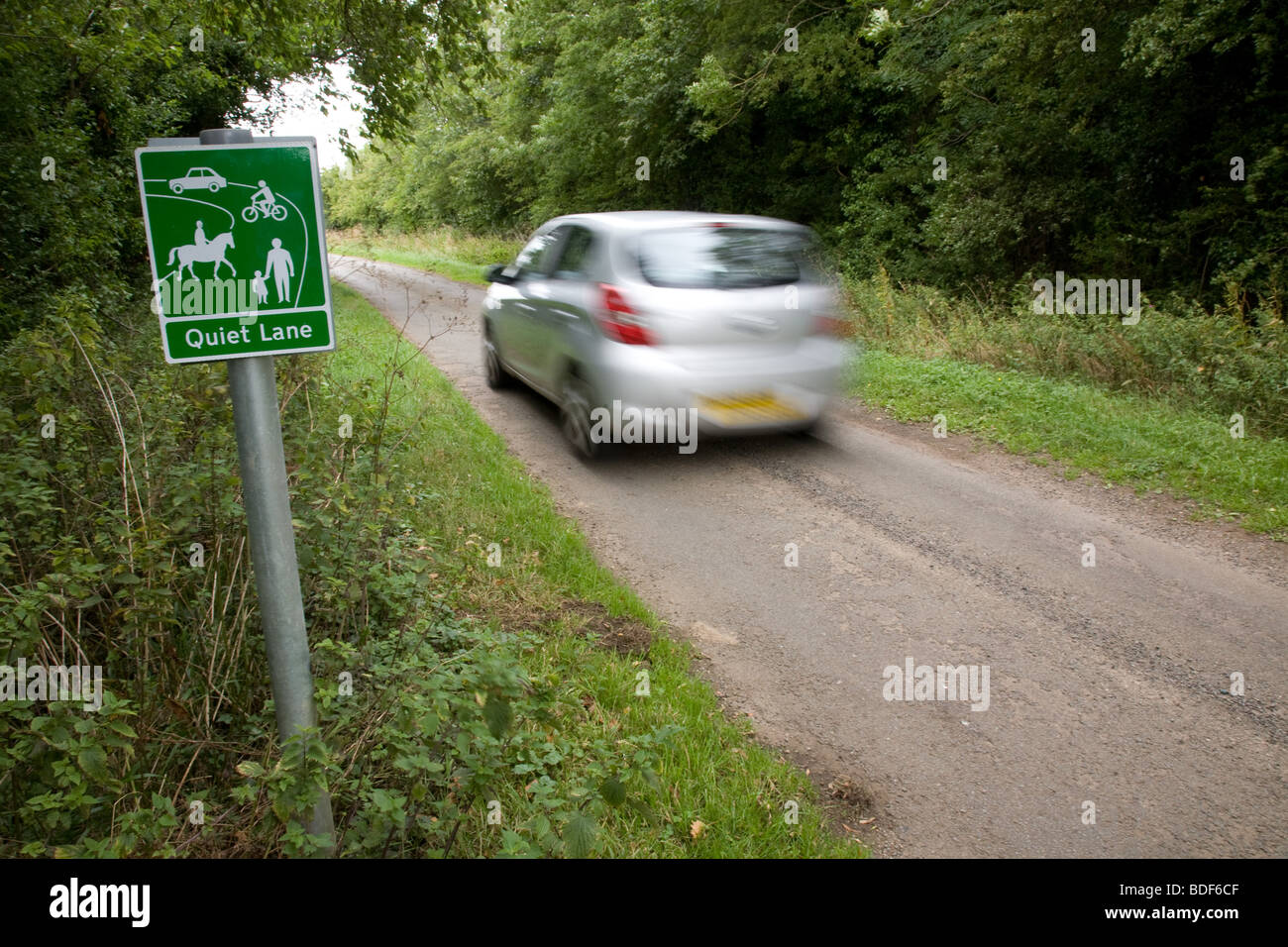 A Car Speeds past a quiet lane sign in a rural lane Stock Photo