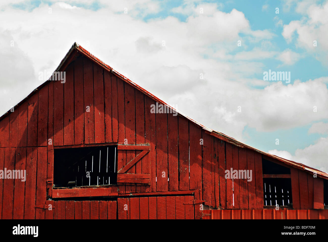 Red tobacco barn against blue sky with clouds in rural Northern