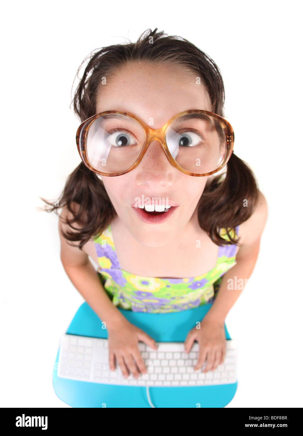 Funny Young Child Working on a Computer Keyboard Looking Up. Fisheye Lens Effect. Stock Photo