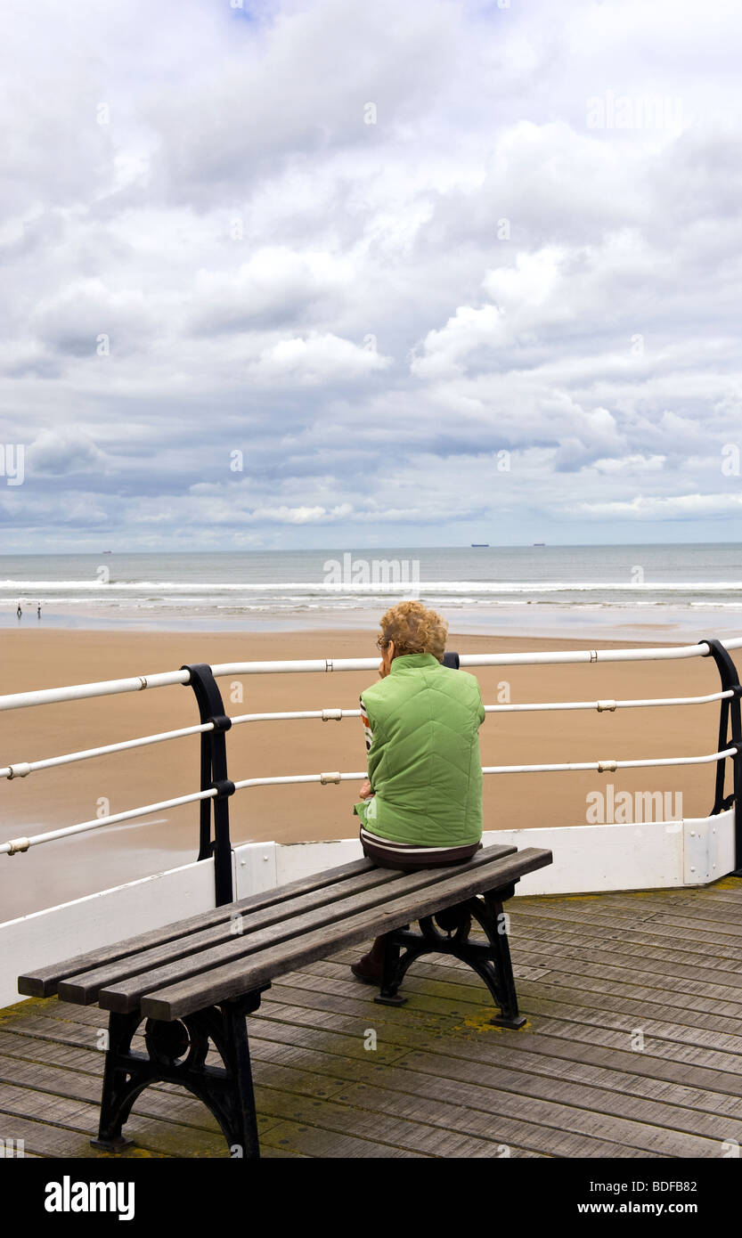 Woman Sat On Bench Looking Out To Sea Stock Photo - Alamy