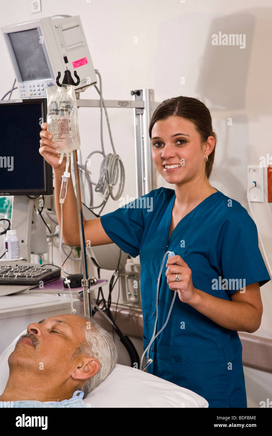 Nurse with IV bag in hospital recovery room with patient Stock Photo - Alamy