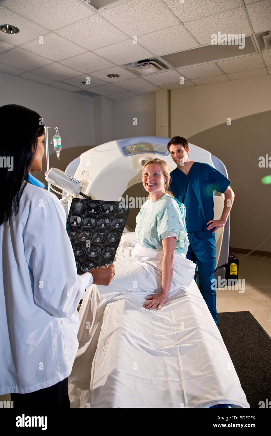 Two healthcare workers looking over CAT scan results with patient Stock Photo