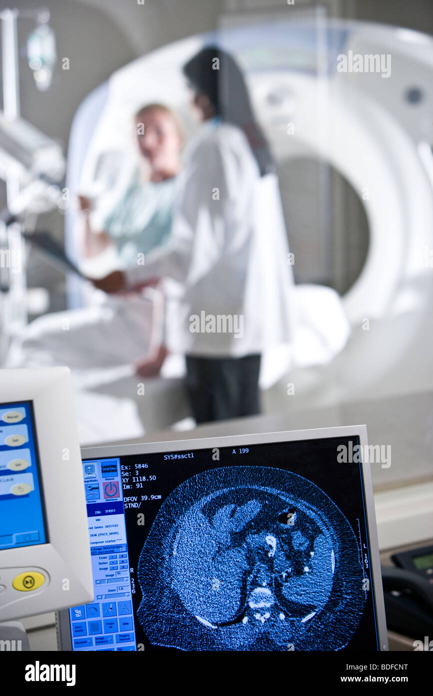 CT scanning equipment with radiologist and patient in background Stock Photo