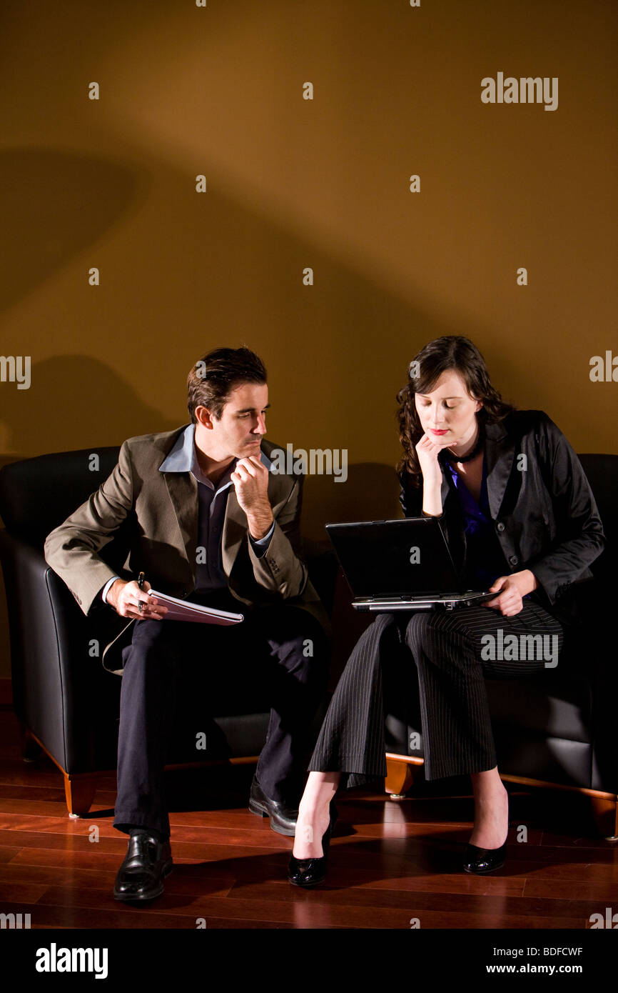 Businesspeople sitting in lounge area with laptop Stock Photo