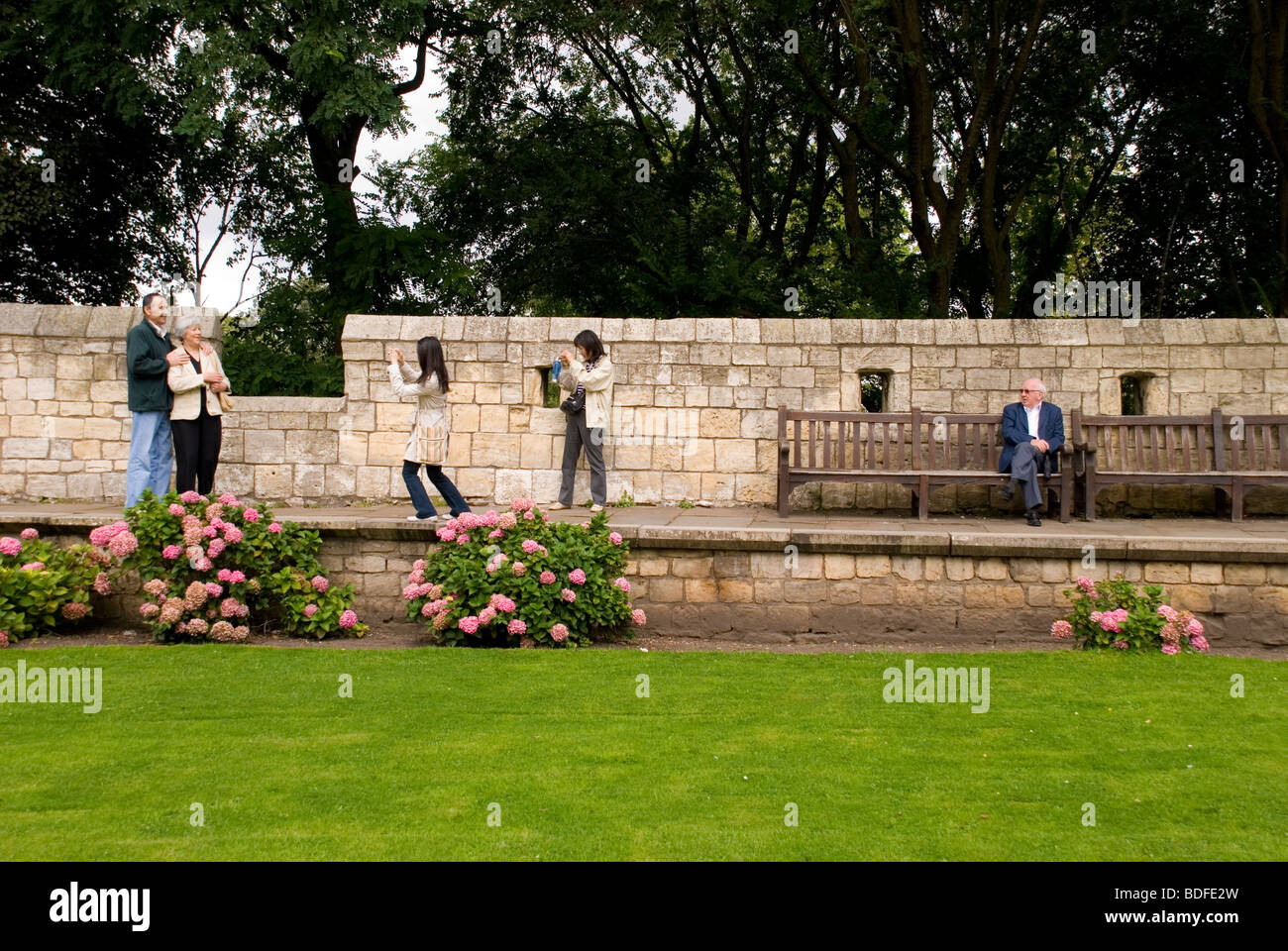 York North Yorkshire England UK A local man watches tourists taking photos on the old city walls Stock Photo