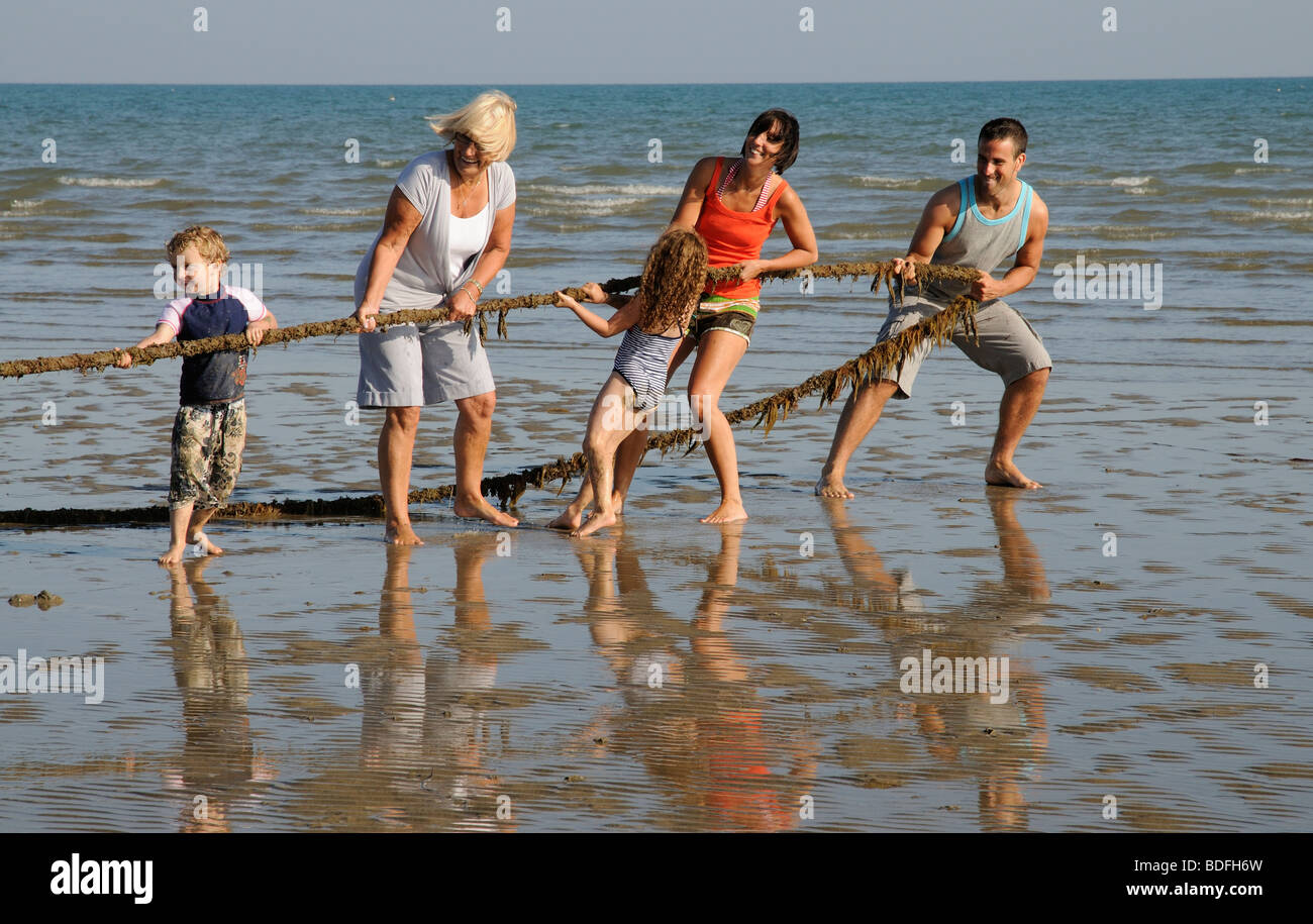 Family holidaying on the beach and enjoying a game of tug of war southern England UK Stock Photo
