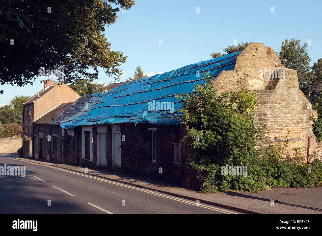 Long roof being renewed covered in blue polythene Stock Photo