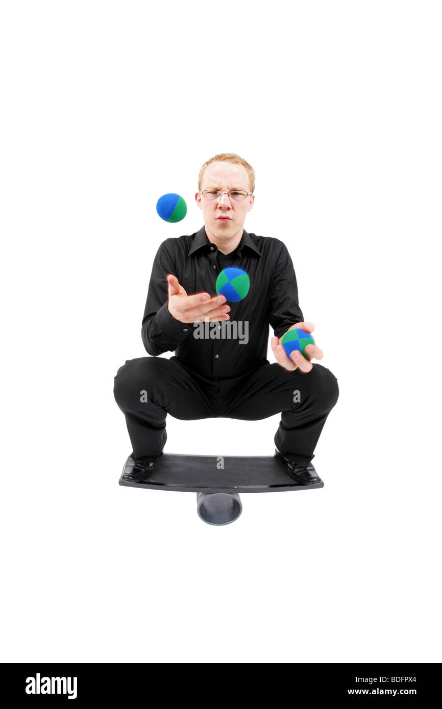 young man juggling with balls and balancing on a rola bola balance