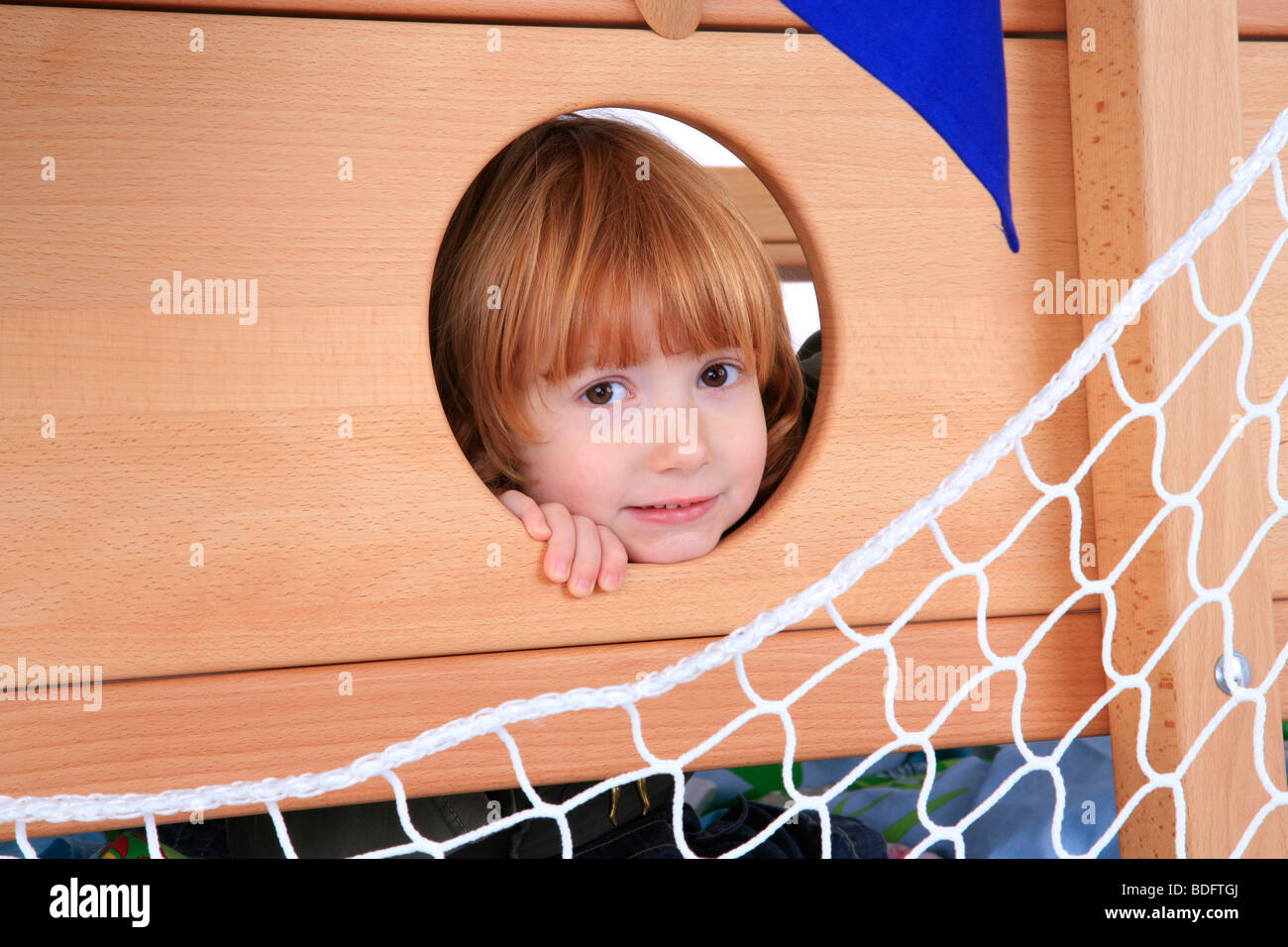 little girl playing in a Billi-Bolli loft bed looking through a hole Stock Photo