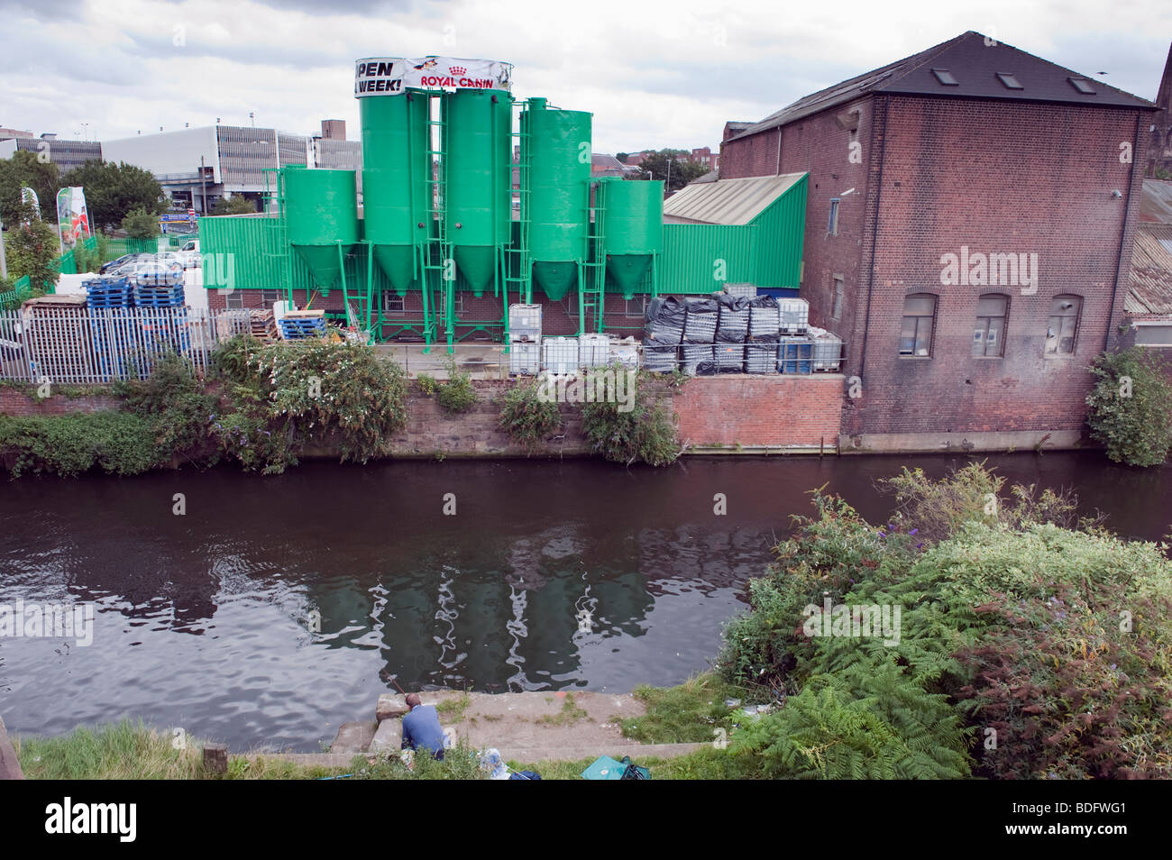 Angler fishing on the Sheffield and South Yorkshire Navigation canal in an industrial setting in Rotherham Stock Photo