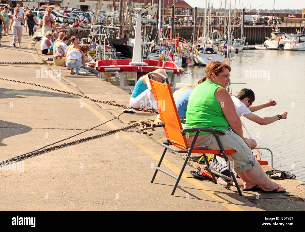 People line the quay side at Wells-next-the-Sea fishing for crabs Stock Photo