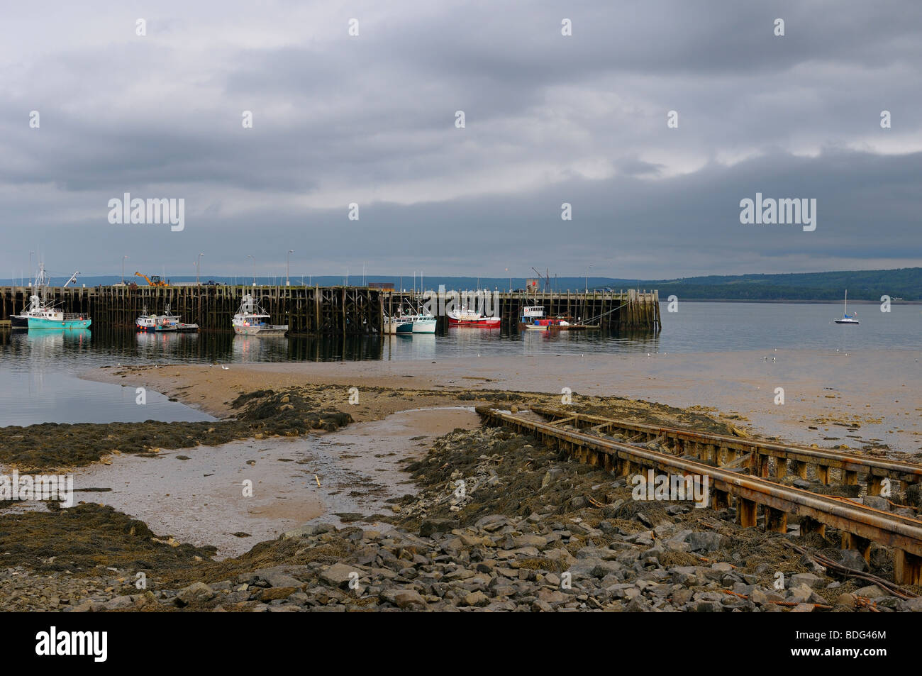 Boat Launch ramp and fishing boats at Digby wharf Bay of Fundy Nova Scotia at low tide Stock Photo