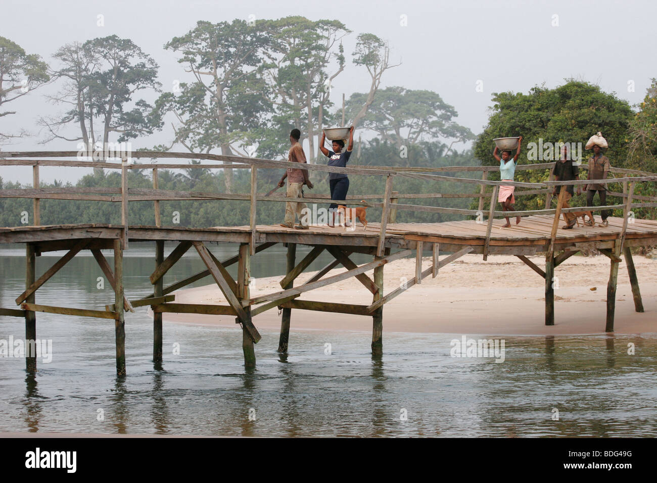 People crossing a footbridge over lagoon. Butre Village. Near Busua. Ghana. West Africa Stock Photo