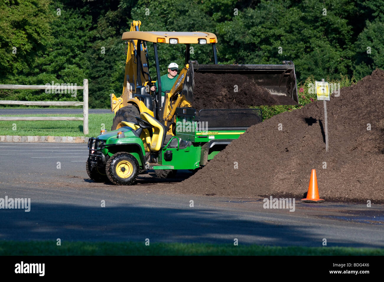 Moving mulch with a John Deere tractor and utility vehicle. Stock Photo