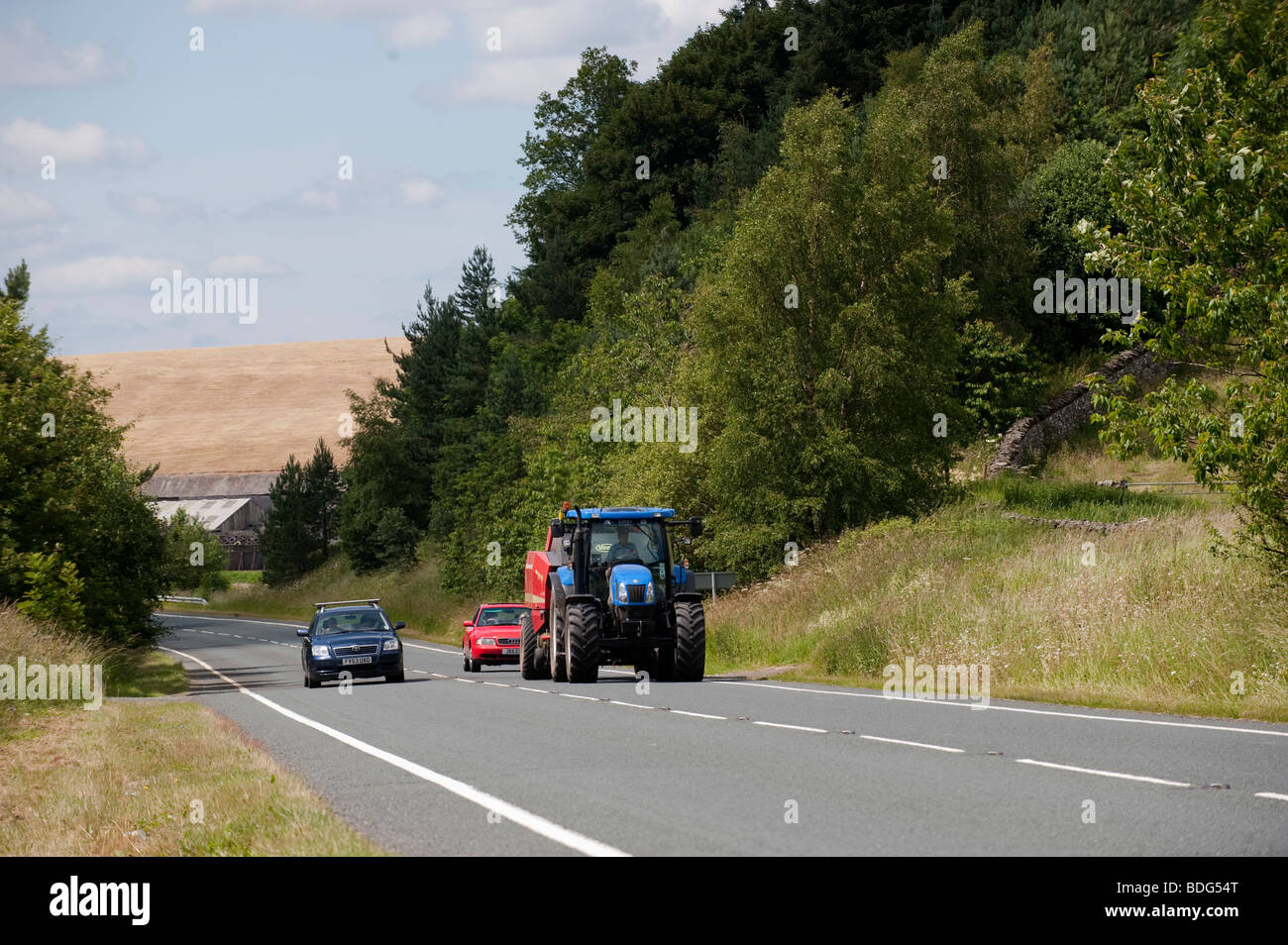 Tractor being overtaken by a car on a country road. Stock Photo
