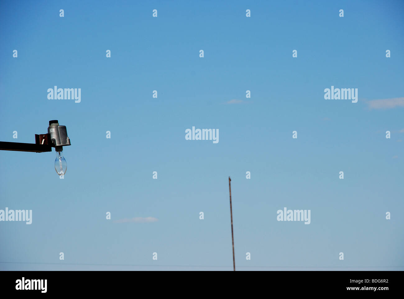 Light bulb against clear blue sky with pole in background Stock Photo