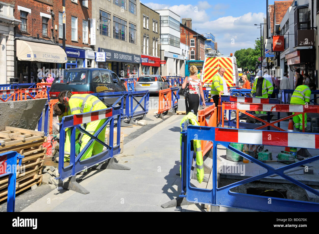 Brentwood shopping high street road works workmen in high visibility jackets upgrading road & pavement disrupting traffic & pedestrians Essex England Stock Photo