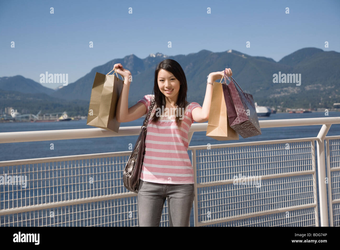 A young woman poses with shopping bags at Canada Place, Vancouver