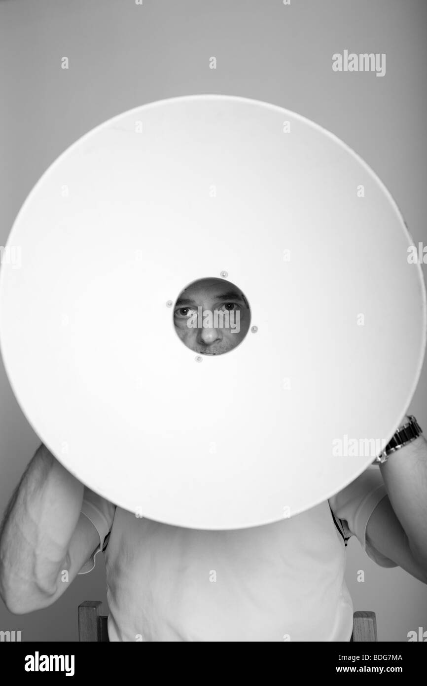 Unusual BW image of a man looking through a beauty dish (basically a reflector for studio lights). Stock Photo