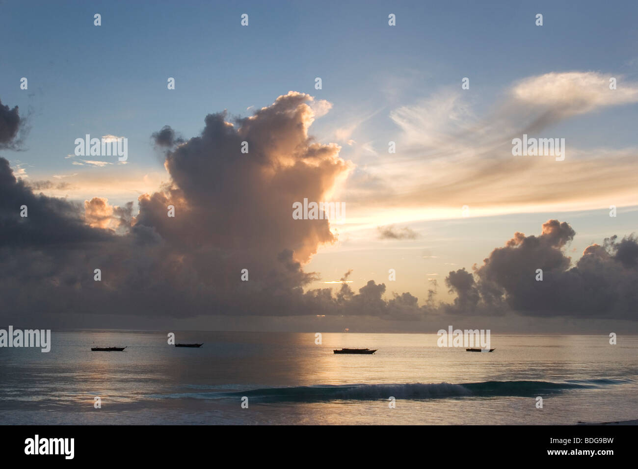 Billowing clouds at a dawn sunrise over Paje Beach, Zanzibar. Dramatic golden clouds form in the sky over the ocean. Stock Photo