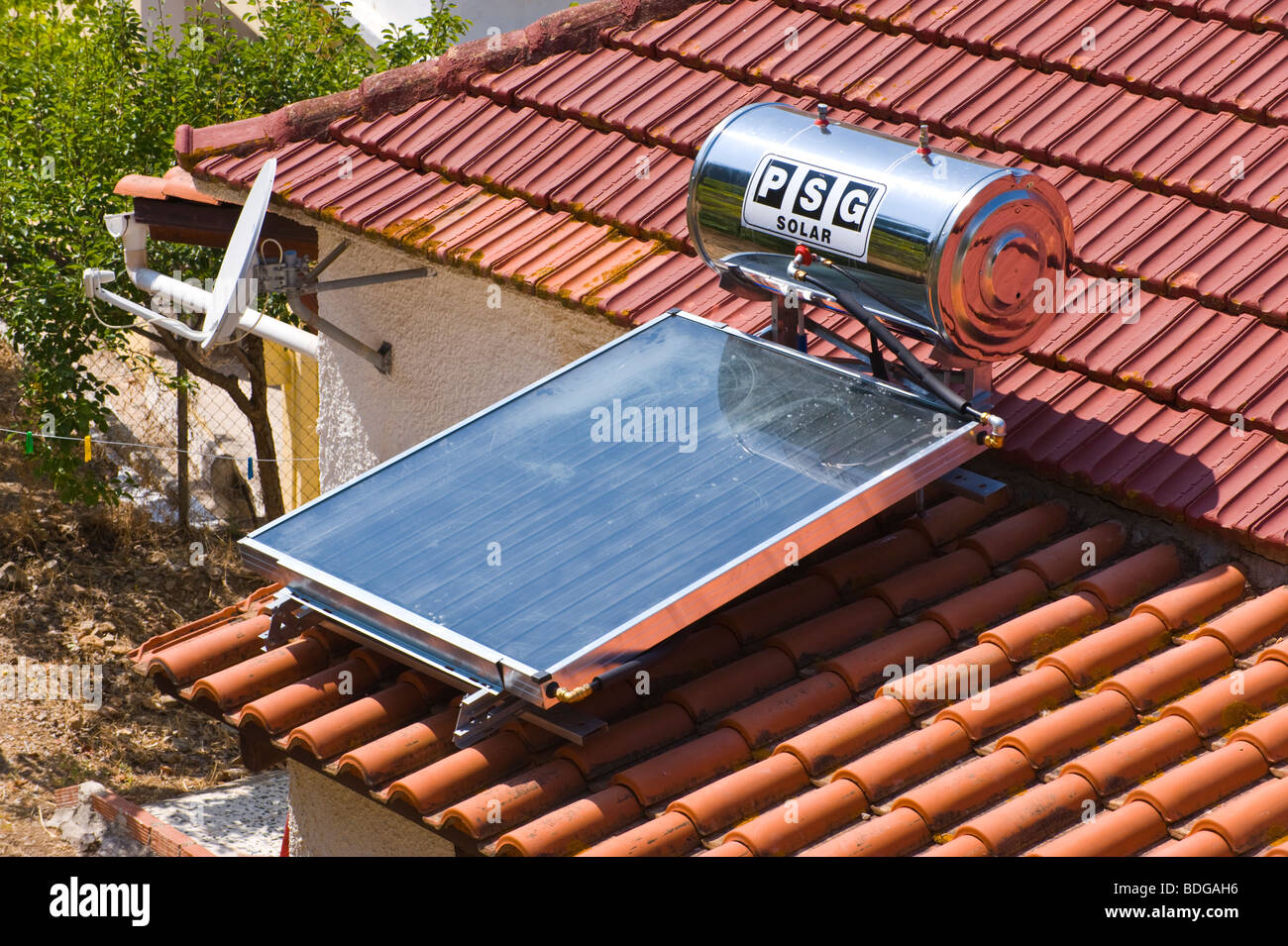 Domestic solar panel water heater on tiled roof of house at Assos on the Greek Mediterranean island of Kefalonia Greece GR Stock Photo