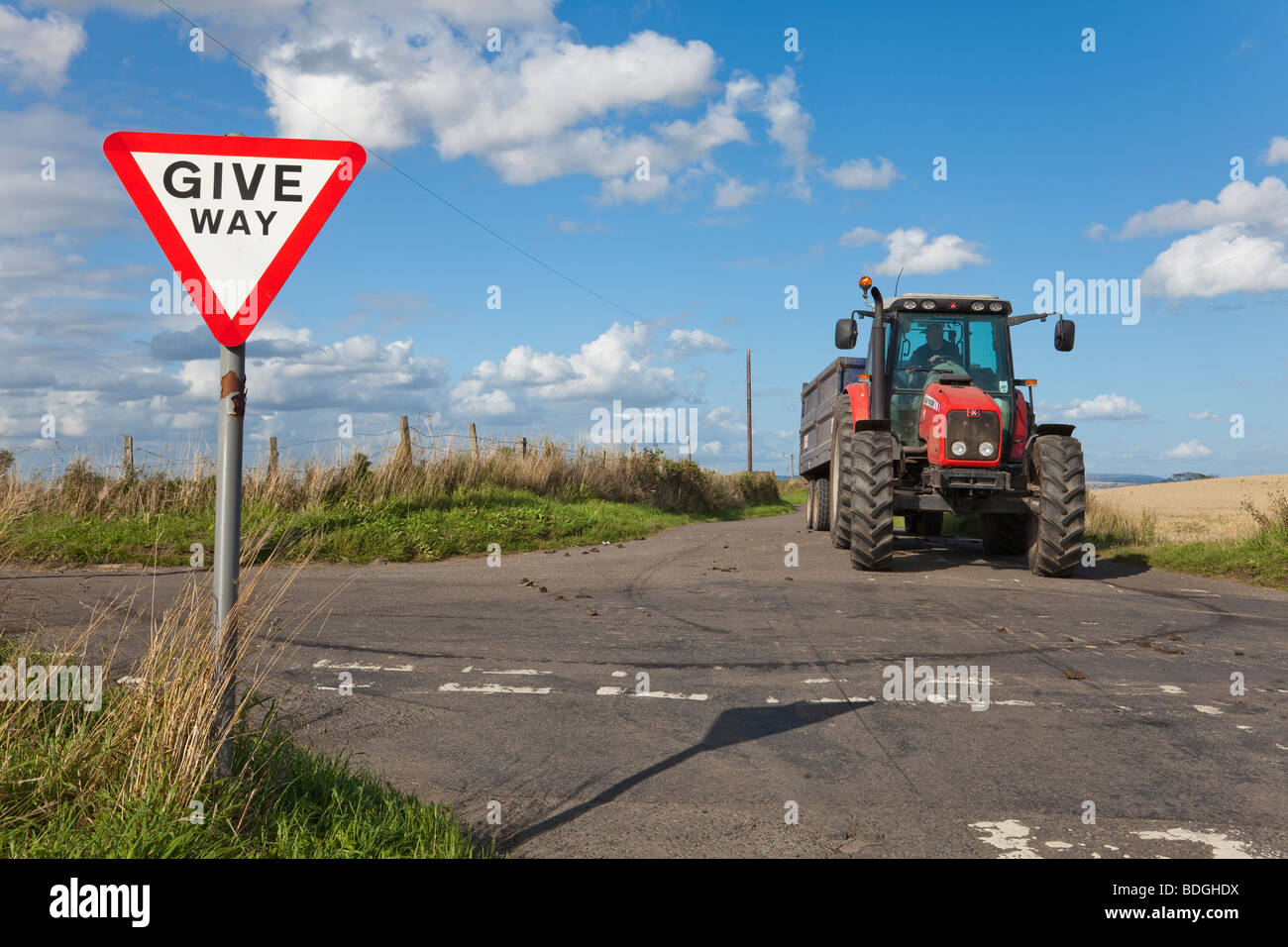 Tractor at crossroads with Give Way sign Stock Photo