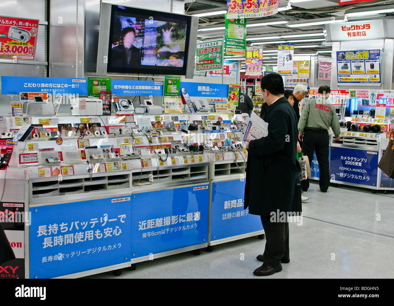 Man reviewing digital cameras in Japanese electronics shop, Tokyo Japan