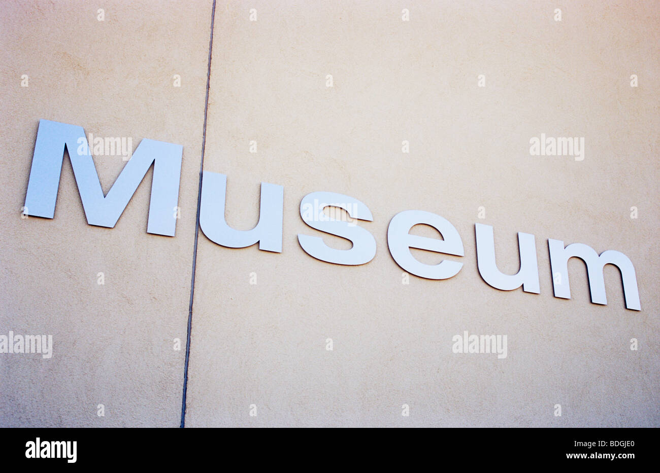 Plain off-white wall with aluminium lettering catching the light ...
