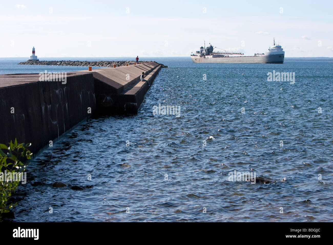 The breakwater and lighthouse at Marquette, Michigan with a passing freighter. Stock Photo