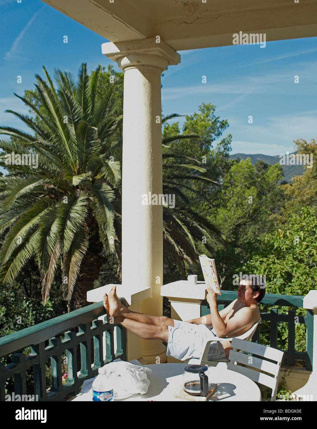 man sitting on chair reading a newspaper in the South of France on a balcony Stock Photo