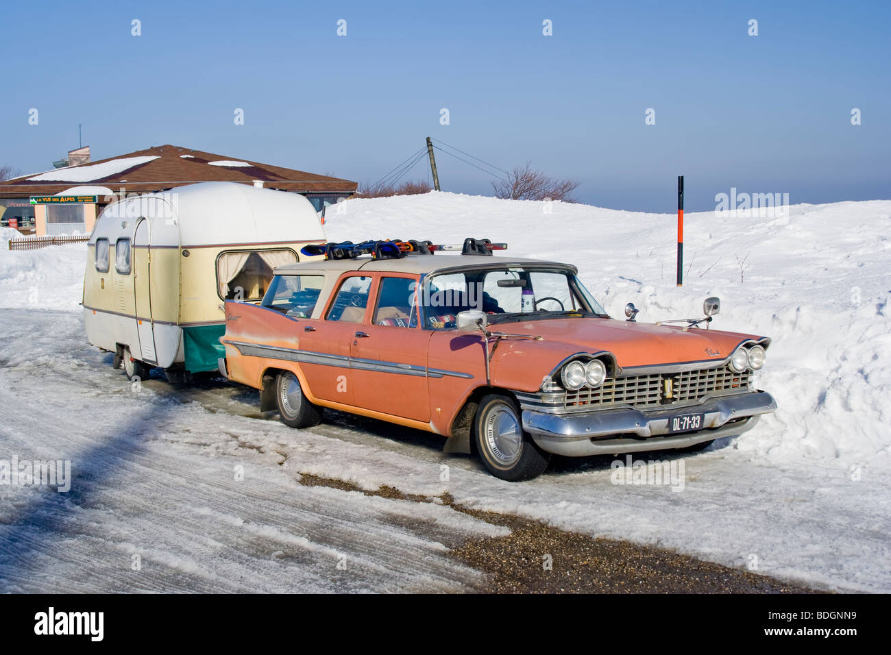 Vintage pink american car with small caravan on snowy landscape, Alsace France Stock Photo