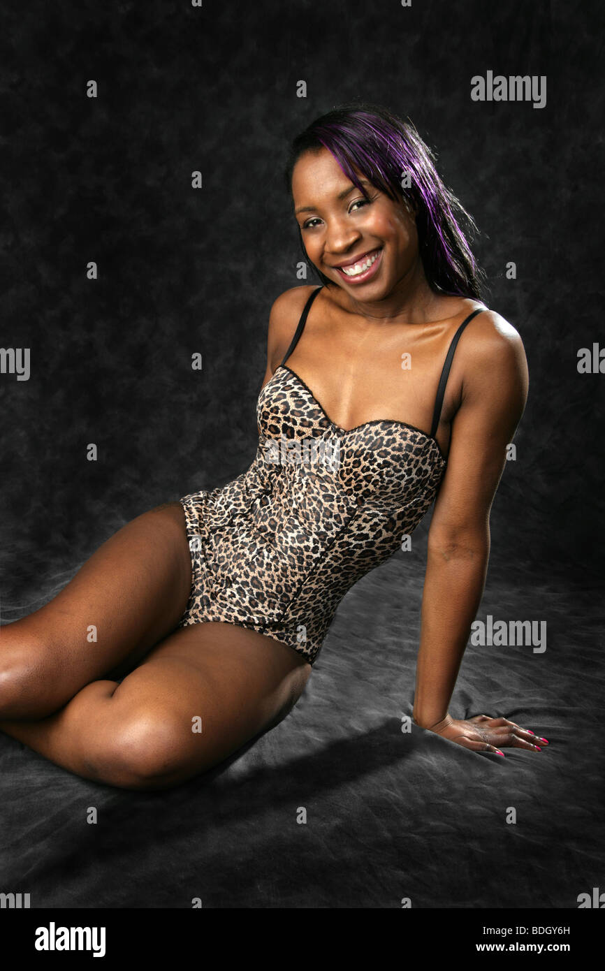 Young Black Woman in a One Piece Leopard Skin Patterned Swimsuit Sitting on the Floor. Stock Photo