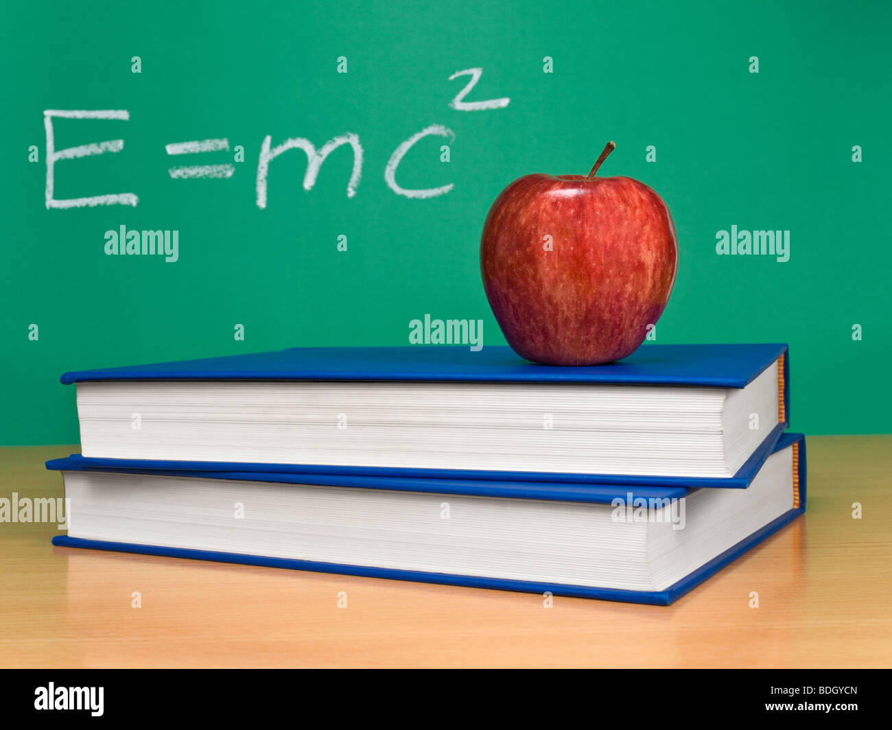 Einsteins formula of theory of relativity on a chalkboard. An apple