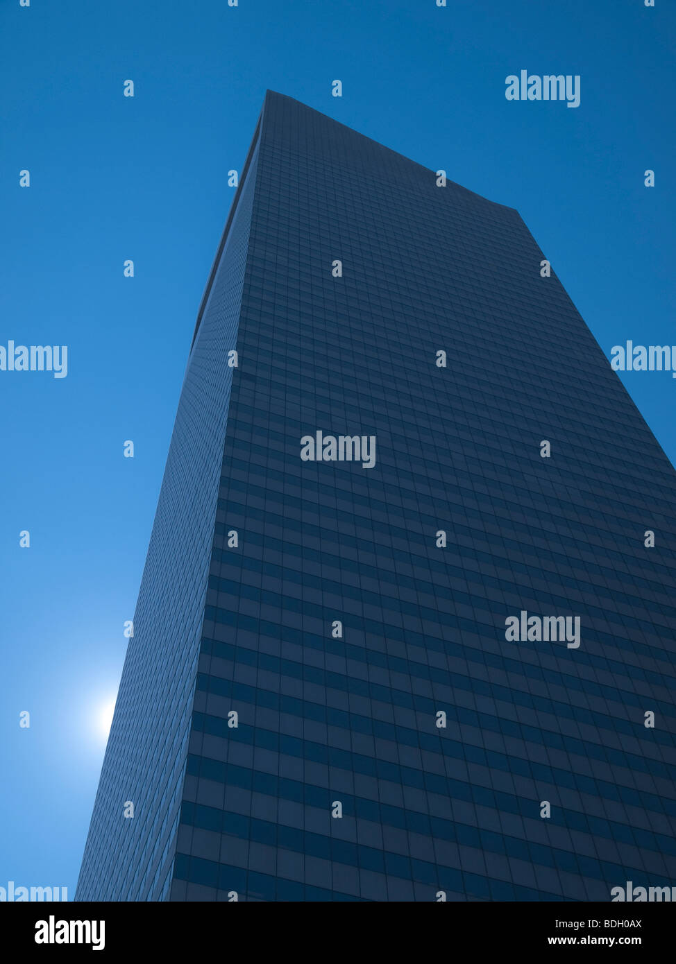 High modern skyscraper on a background of a blue sky and the sun. Stock Photo