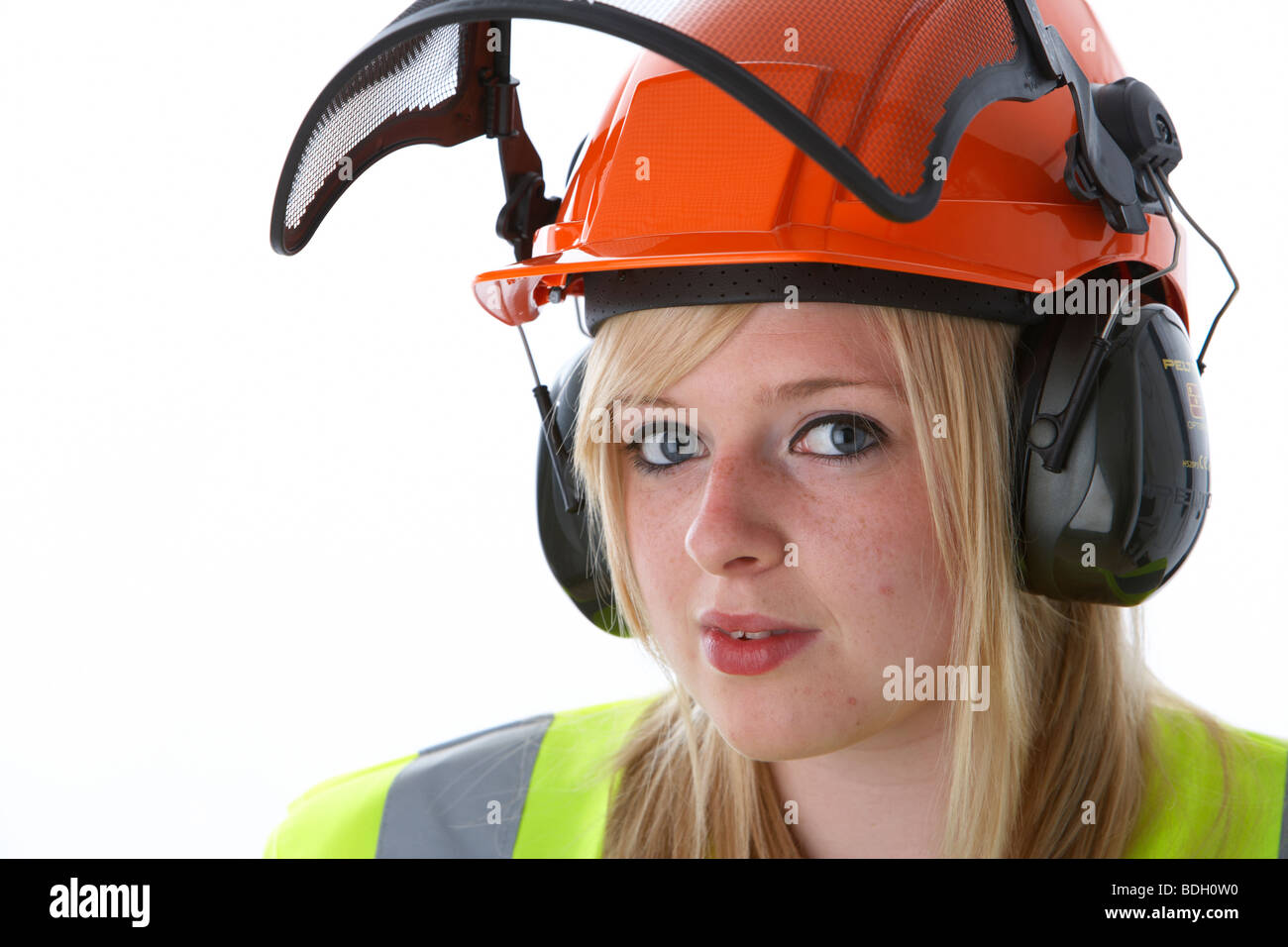 young 20 year old blonde woman wearing orange hard hat ear protectors visor and high vis vest eye contact Stock Photo