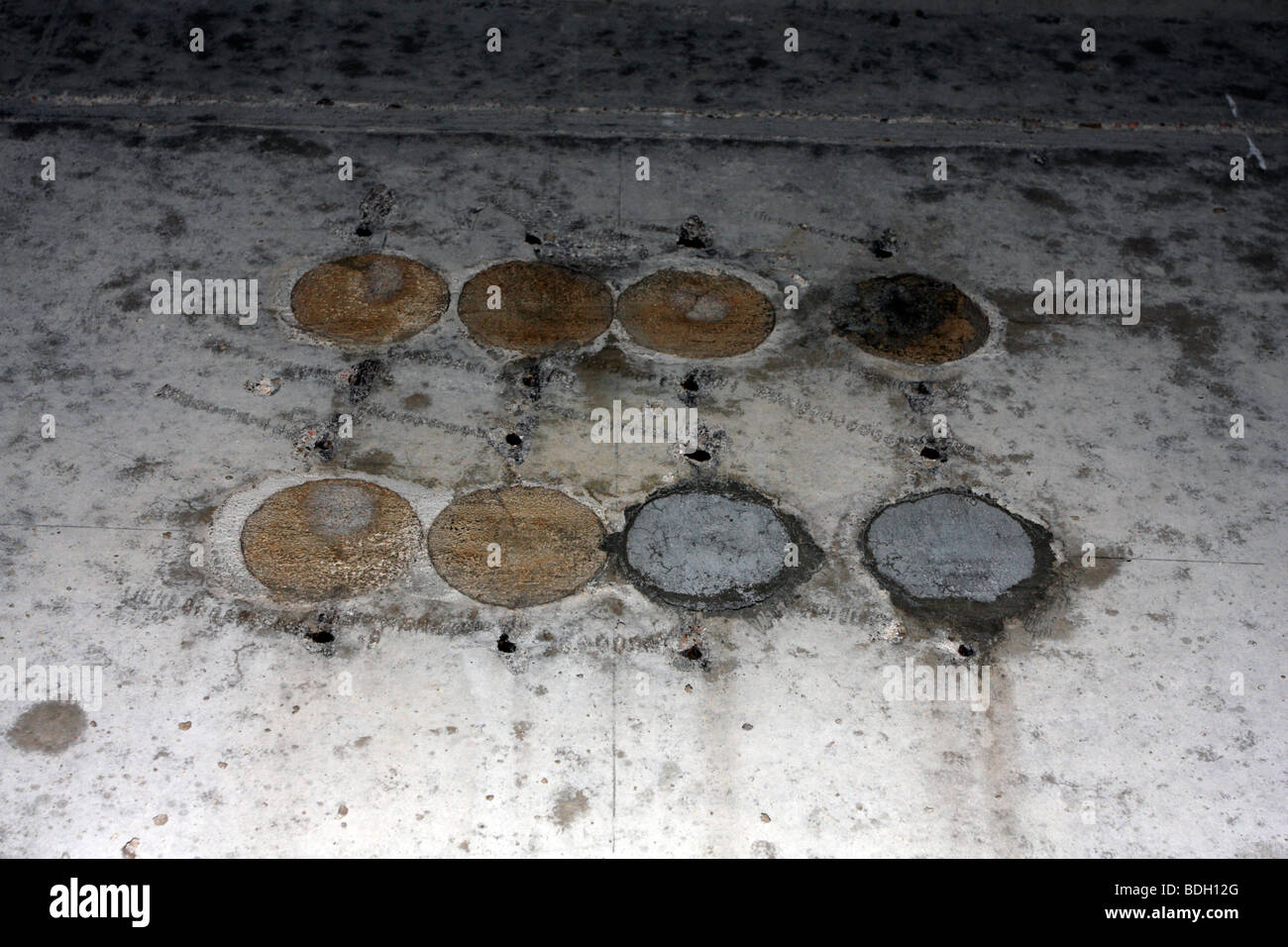 A row of post-tensioning plug holes on concrete face, showing discoloration and staining. Stock Photo