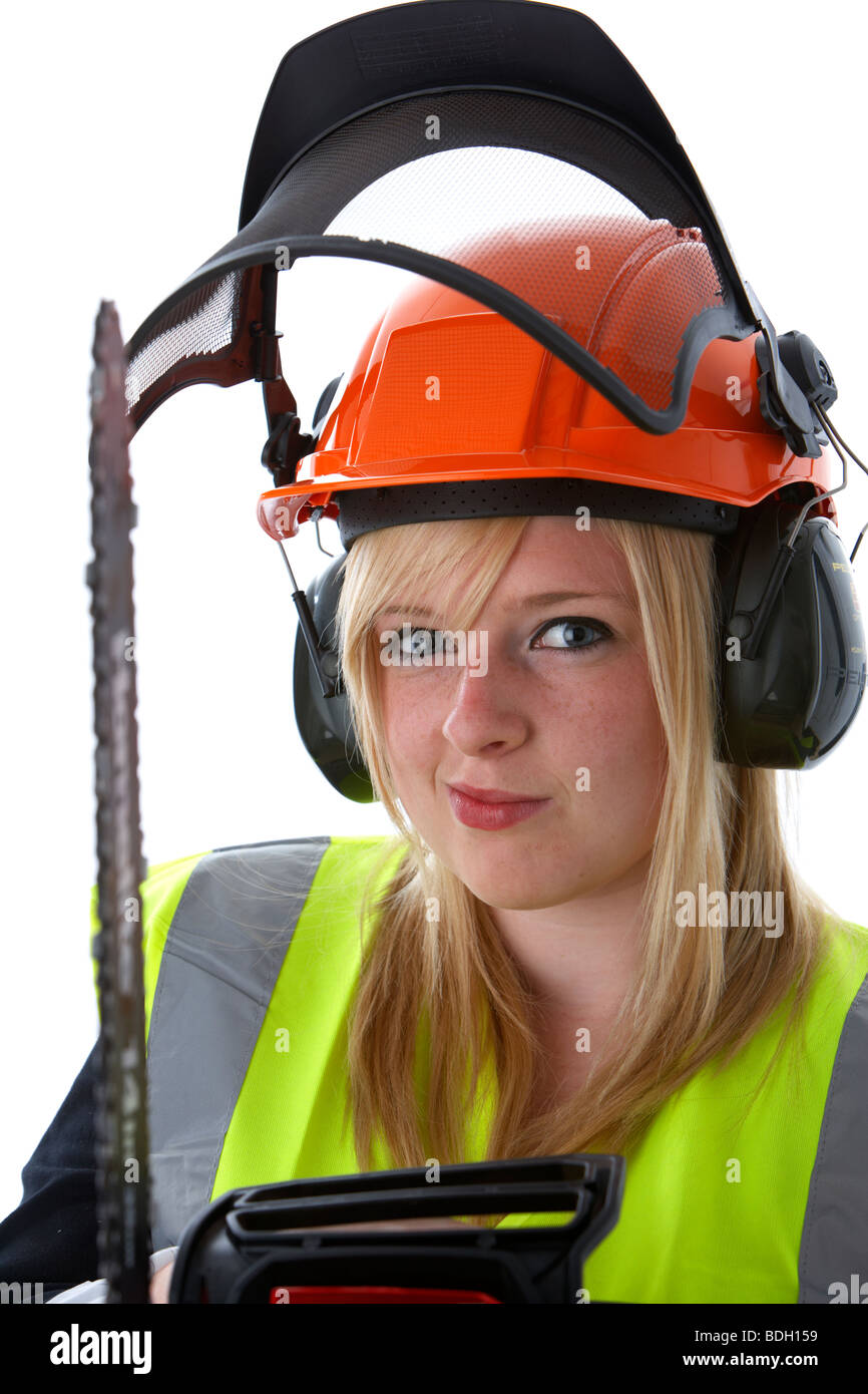 young 20 year old blonde woman wearing orange hard hat ear protectors visor and high vis vest holding chainsaw Stock Photo
