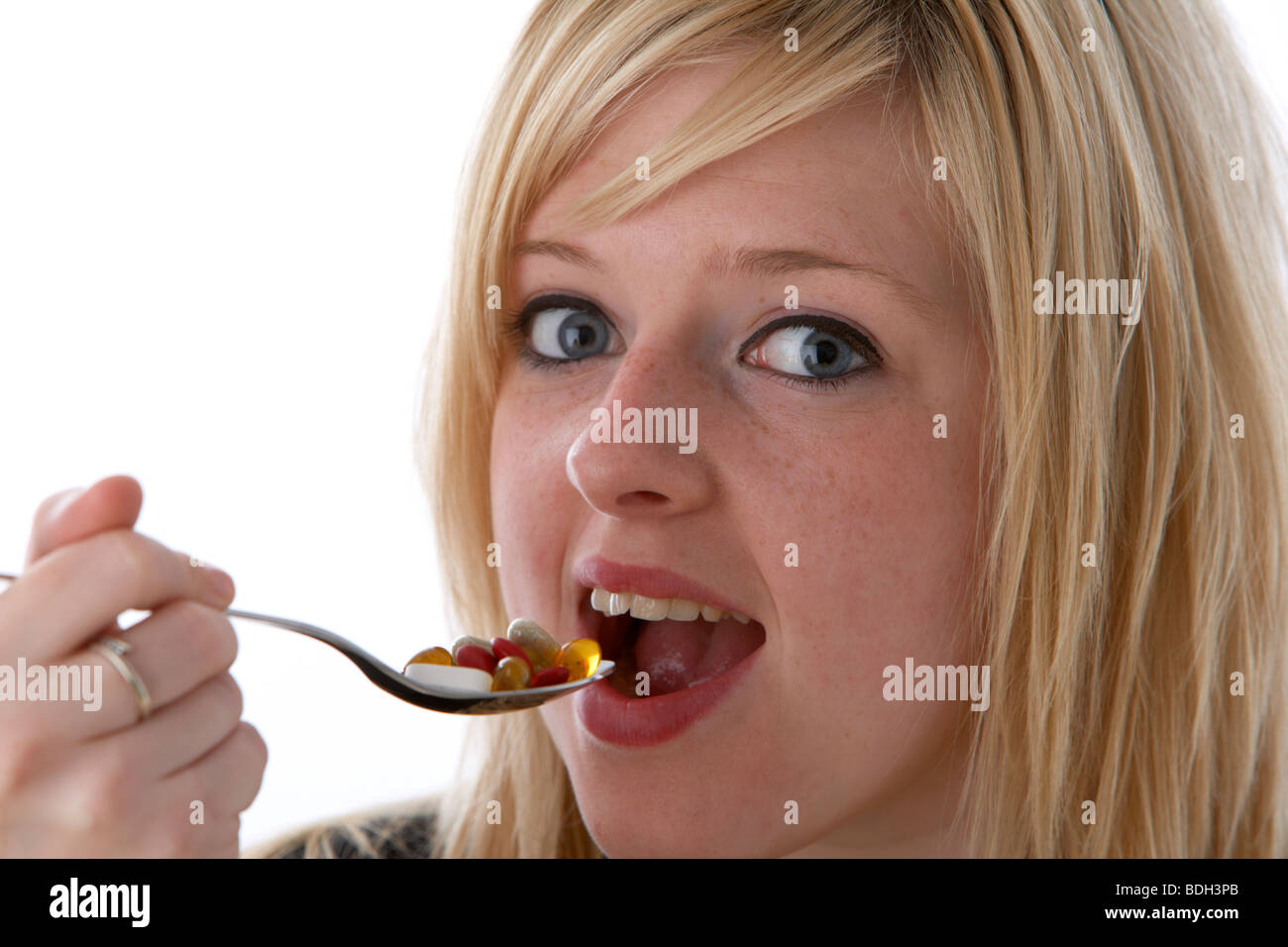 young 20 year old blonde woman taking a spoonful of vitamin supplements Stock Photo