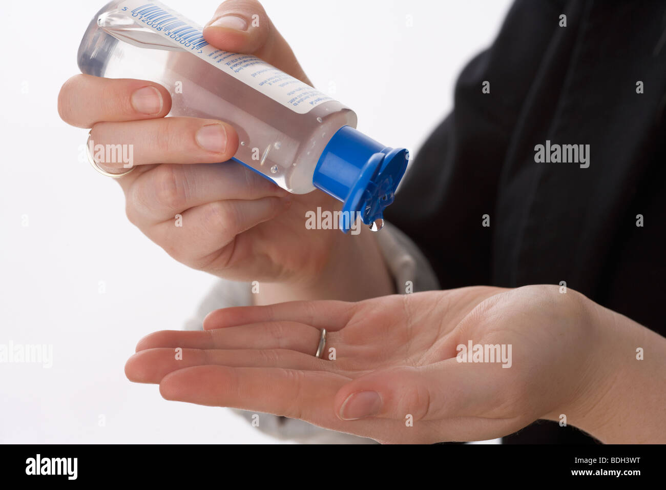 young 20 year old woman cleaning her hands with an alcohol gel hand santizer to kill infection and bacteria using hand sanitiser against virus Stock Photo