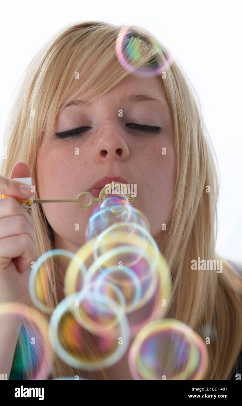 young 20 year old blonde woman blowing bubbles from a childs toy Stock Photo