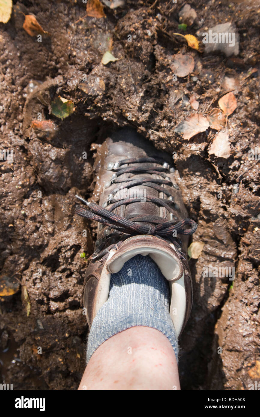 Person hiker wearing a leather walking boot sinking in deep mud seen from above. UK Stock Photo