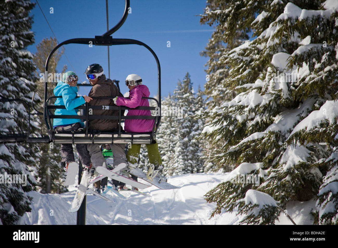 Three happy skiers on a chair lift on a sunny day in California. Stock Photo