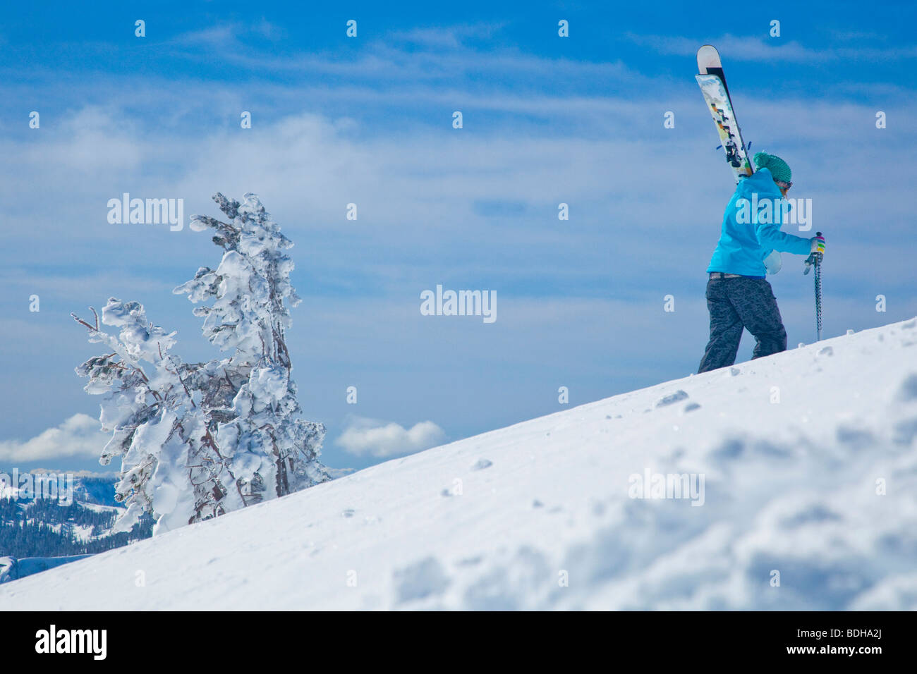 Female skier hiking up to a backcountry peak on a sunny day in California. Stock Photo