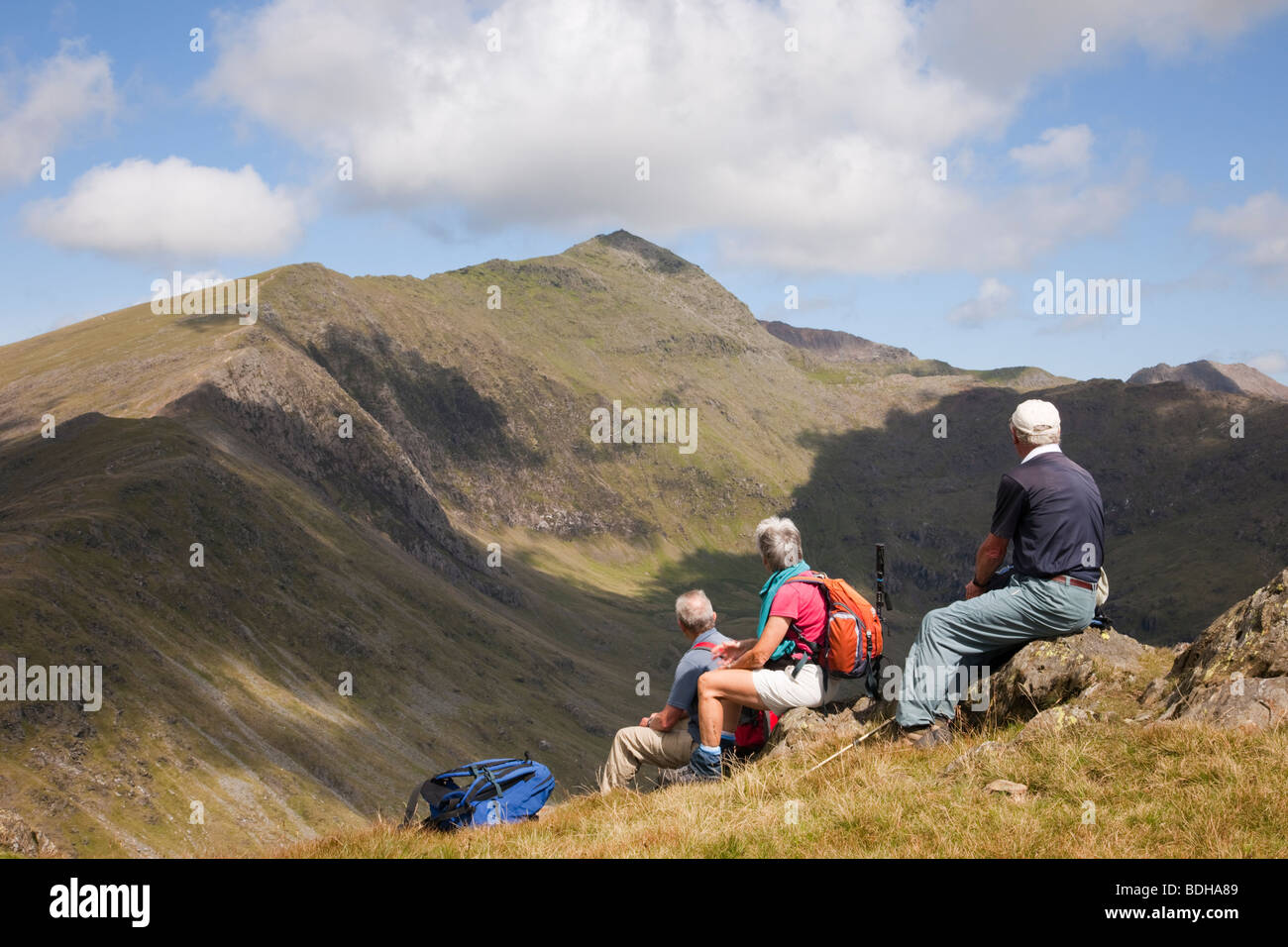 Three walkers on Yr Aran looking across Cwm Llan towards Mount Snowdon in Snowdonia National Park North Wales UK Britain. Stock Photo