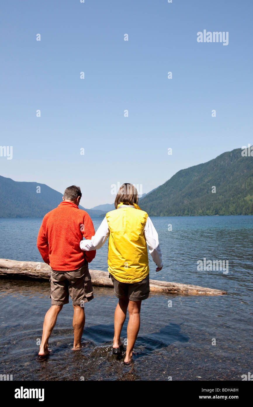 A woman holds a mans arm while walking out to a log in a lake Stock Photo -  Alamy