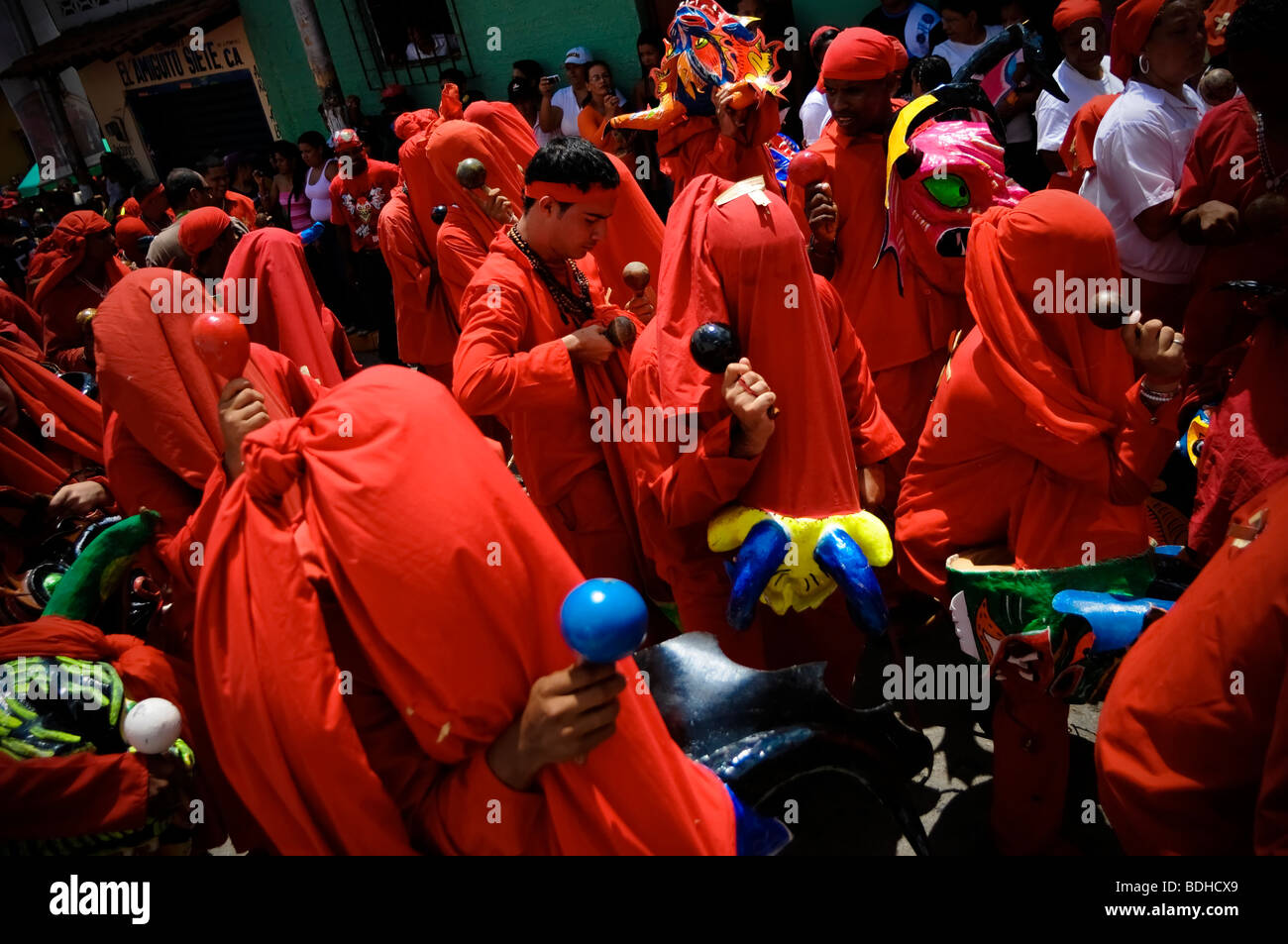 Men dressed in red costumes dance with maracas to celebrate a festival Stock Photo